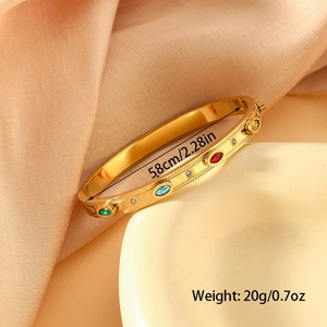 Golden stainless steel eye bangle with colorful zircon stones on a ceramic plate