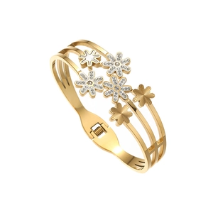 Detail of gold titanium steel bangle featuring cutout daisies and shimmering crystal inlay