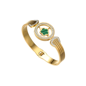Detail of gold floral bangle with green clover stone inlay and white zircon accents