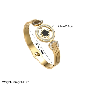 Polished gold cuff bracelet featuring black clover pendant with white crystals