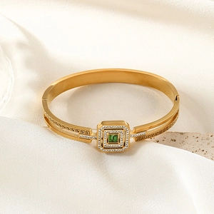 Gold hollow cuff bracelet with green square gemstone and Greek key engraving details