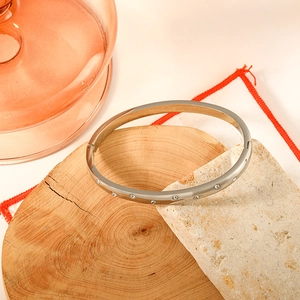 Minimalist silver tone stainless steel bangle with inlaid zircons on a wooden background
