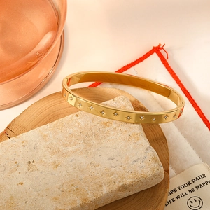 Golden stainless steel bangle featuring starburst engravings and cubic zirconia stones