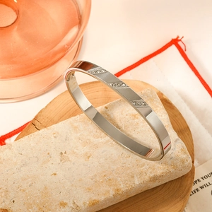 Silver polished stainless steel bangle with nine crystals on a stone display