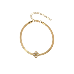 Detailed close-up of a golden snake chain bracelet with a sparkling clover crystal charm