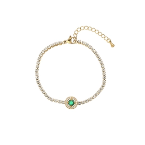 Detail eines goldenen Tennisarmbands mit smaragdgrünem Mittelstein und Zirkonia-Steinen