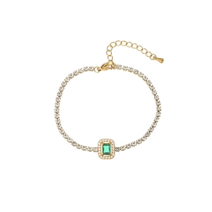 Detail eines goldenen Tennisarmbands mit smaragdgrünem Edelstein und Karabinerverschluss
