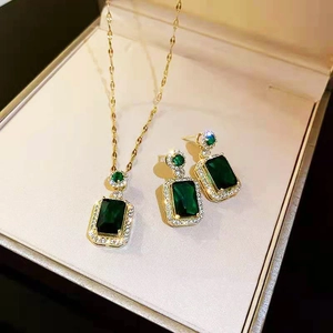 Elegant gold titanium steel jewelry set featuring emerald green rectangle stones with halo