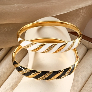 Eleganti bracciali a spirale dorati con smalto nero e bianco e cristalli incastonati