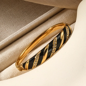 Bracciale dorato a spirale con smalto nero e micro cristalli su sfondo elegante