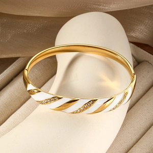 Dettaglio del bracciale a spirale dorato con smalto bianco e micro-zirconi incastonati