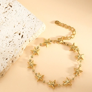 Detail view of gold stainless steel star bracelet with adjustable lobster clasp on marble