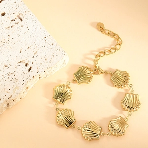 Detailed close-up of golden shell-shaped link bracelet with lobster clasp and extension chain