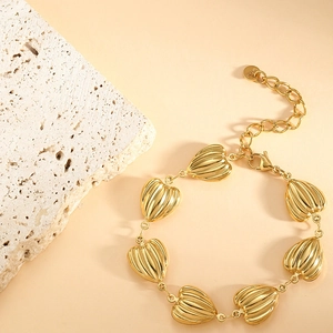 Close-up of golden stainless steel heart charms with striped texture and lobster clasp
