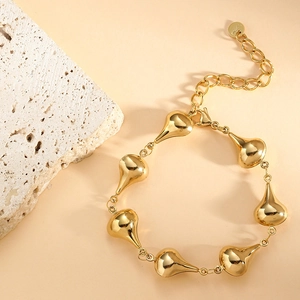 Detail of golden stainless steel teardrop bracelet with adjustable chain and logo tag