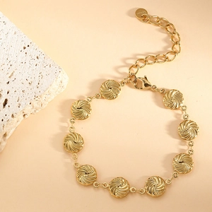 Detail of gold-plated stainless steel bracelet with spiral textured circular discs