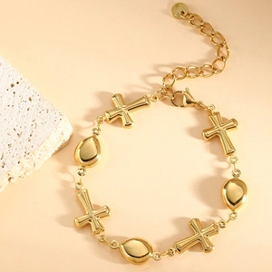 Detail shot of golden cross and teardrop charms on a polished stainless steel bracelet