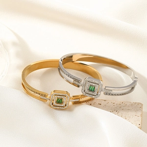 Gold and silver hollow geometric bangles with Greek meander pattern and green gemstone