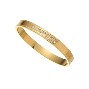 Polished gold stainless steel bangle with seven inset cubic zirconia and textured edges