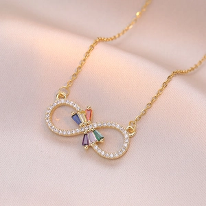 Collar infinito dorado con circonitas de colores sobre un fondo de seda rosa suave