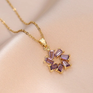 Goldene Titanstahlkette mit lila Zirkonblüten-Anhänger auf champagnerfarbenem Satin-Stoff
