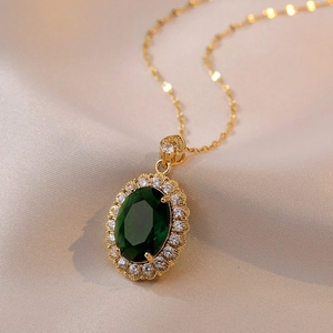 Vintage style golden necklace featuring an oval emerald green stone and zircon halo