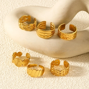 Set of six gold stainless steel open rings with varied vintage textures on ceramic display