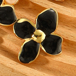 Macro detail of four-petal flower stud earring with black enamel and gold stainless steel