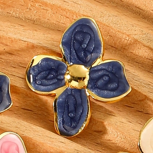 Macro view of blue enamel four-leaf flower earring with gold-plated stainless steel edges