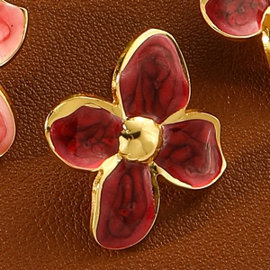 Elegant four-petal flower earrings in gold with deep red enamel on brown leather