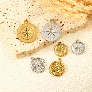 North Star 18K gold and silver compass pendants displayed on textured stone