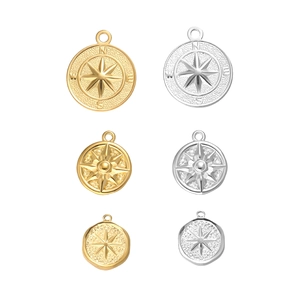 Detail of 18K gold and silver North Star compass charms with embossed star patterns