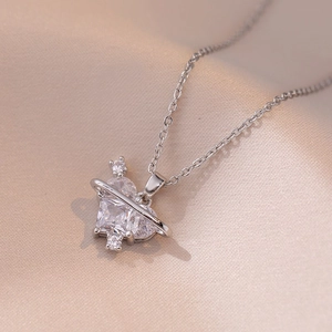Silver heart saturn pendant necklace with sparkling zircons on silk background