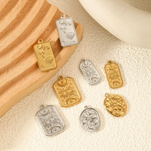 Golden and silver tarot pendants with stars and moon engravings on a wooden stand