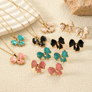 Elegant gold titanium bow necklace and earring set in pink, blue, black, and white colors