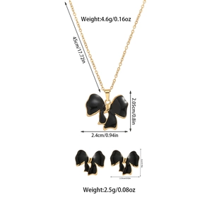 Detailed view of black enamel bow necklace and earring set with size specifications