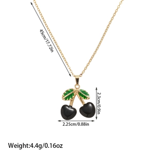 Detailed macro view of cherry pendant necklace with black fruit and green enamel leaf detail