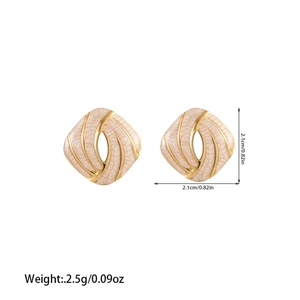 Detail view of square gold earrings with cream textured enamel and precise dimensions