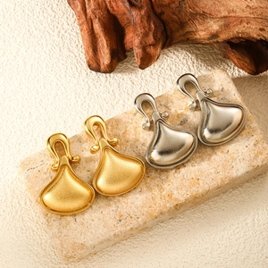 Detailed view of U-shaped gold and silver teardrop earrings on a stone textured base
