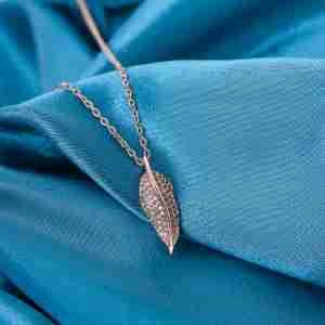Détail du collier pendentif feuille en or rose avec zircons micro-pave sur soie bleue