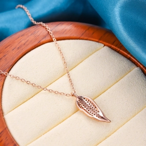 Elegant rose gold leaf necklace on a luxury wood jewelry box with velvet lining