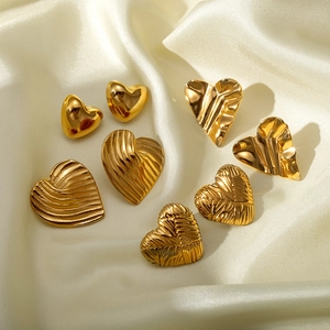 Golden titanium steel heart earrings set with multiple textured finishes on satin