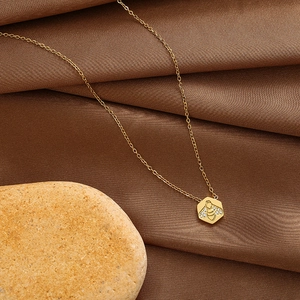 Detail eines goldenen Sechseck-Anhängers mit gravierter Biene und Kristallen
