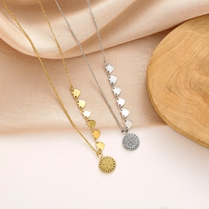 Detalle de collares de titanio en oro y plata con dijes de corazón sobre tela suave