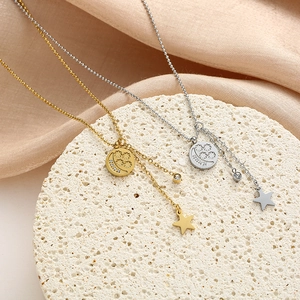 Detalle de dijes de estrella y luna en un collar de acero de titanio dorado y plateado