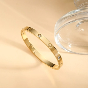 Bracciale rigido in acciaio inossidabile dorato con motivi a quadrifoglio e zirconi bianchi