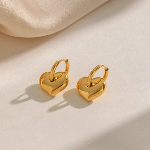 Detail of golden heart-shaped charms on hoop earrings with minimalist metal finish