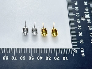 Detailed view of polished gold and silver bean stud earrings with a scale for size reference