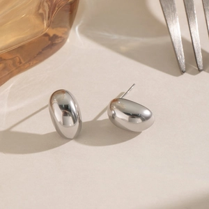 Detailed close-up of silver bean stud earrings with high-polish mirror finish