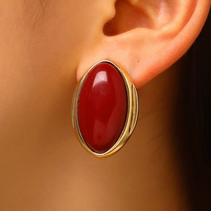 Close-up detail of a vintage red oval resin stud earring with gold-tone rim on ear